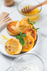 syrniki with honey on a white plate