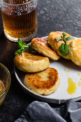 syrniki with honey on a white plate