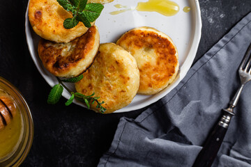 syrniki with honey on a white plate