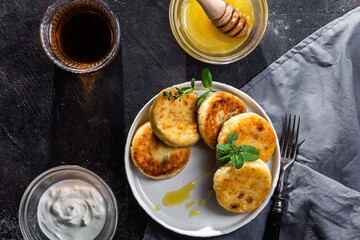 syrniki with honey on a white plate