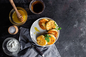 syrniki with honey on a white plate