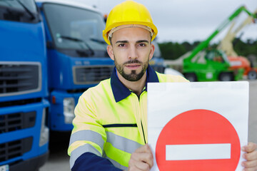 man in reflective clothing holding a no entry sign