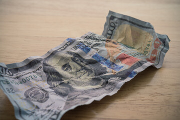 Crumpled $100 US dollar bill banknote on wooden table background. Global world economy recession...