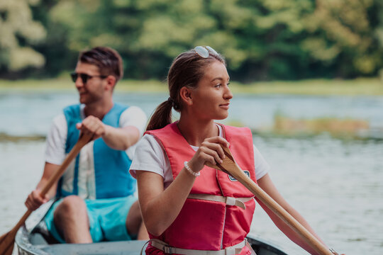 Couple Adventurous Explorer Friends Are Canoeing In A Wild River Surrounded By The Beautiful Nature