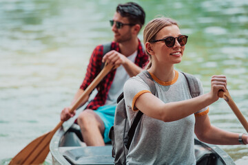 Couple adventurous explorer friends are canoeing in a wild river surrounded by the beautiful nature
