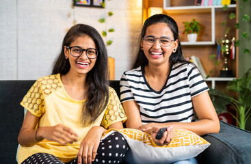 happy siblings laughing while watching comedy show or movie on tv or television - concept of...