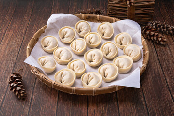 Korean handmade dumplings. Kimchi dumplings in a basket before roasting in a steamer. Wood deck background.