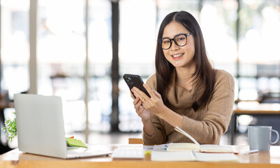 Portrait of Happy Excited young asian woman at workplace office desk, successful Asian female reading good news technology online, employee freelance finance concepts.