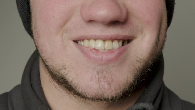 Close-up beauty portrait of a young man with smooth, healthy skin, natural lips, modestly smiling. Natural and healthy smile of a young man. Straight and healthy teeth. Dental concept