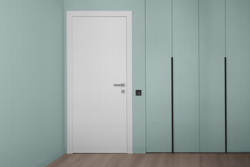 White door on the background of an empty mint wall
