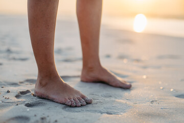Close-up of womans feet in sand, at sea.