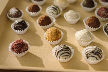 Set of natural healthy chocolate candies on tray. Soft focus. Professional pastry chef or chocolatier. Sweets in paper forms
