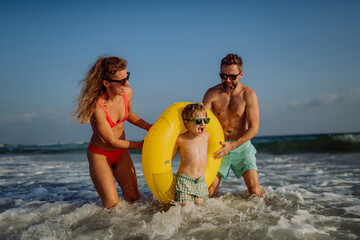 Happy family with little son enjoying time in sea in exotic country.