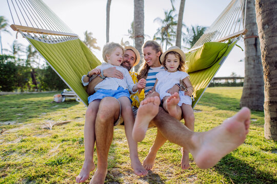 Young family with little kids enjoying their holiday in exotic country, lying in hammock.