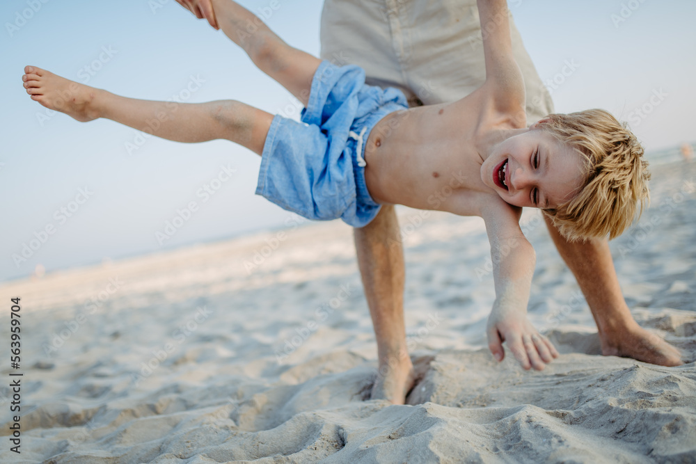 Wall mural father holding his son upside down, enjoying summer vacation, having fun.