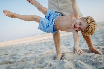 Father holding his son upside down, enjoying summer vacation, having fun.