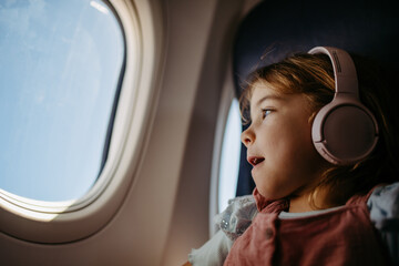 Little girl in airplane looking out of the window.