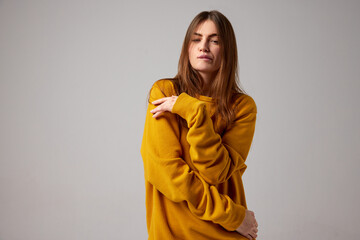 Half-length portrait of fashionable sensual emotional woman wearing trendy yellow sweater posing over gray background. Concept of fashion, style, youth, beauty