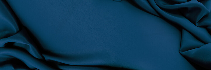 Dark blue silk satin background. Bright folds on a shiny fabric. Valentine's Day. Luxury background with empty space for design. Top view web banner