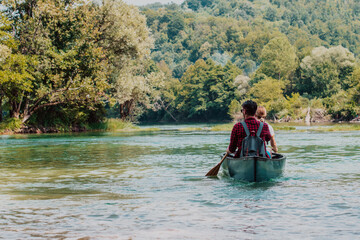 Fototapeta na wymiar Couple adventurous explorer friends are canoeing in a wild river surrounded by the beautiful nature