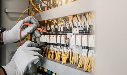 Electrician engineer tests electrical installations and wires on relay protection system.