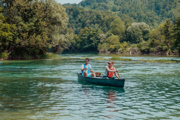Fototapeta na wymiar Couple adventurous explorer friends are canoeing in a wild river surrounded by the beautiful nature