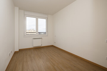 Empty room of a house with a dark colored laminate floor and a white aluminum window with two panes and a view of the city