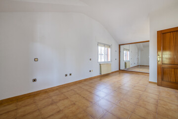 Empty living room with an orange tile floor, plain white walls, a mirrored mural cover, and a...