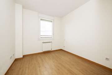 Empty room with light wooden floors, white aluminum radiators, smooth white painted walls and a white aluminum and glass single pane window
