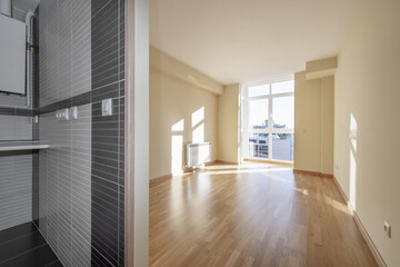 Empty room with light oak hardwood floors in a home with a kitchen without doors