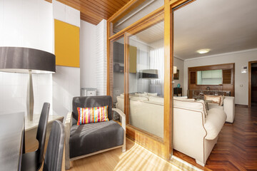 A small closed terrace with glazing next to a spacious living room with white sofas