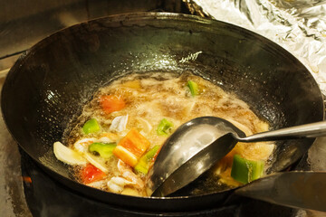 A chef stir frying vegetables and shrimps in an Asian restaurant