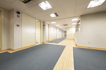An empty long hall hall of an office office with mixed blue carpet and light wood floors