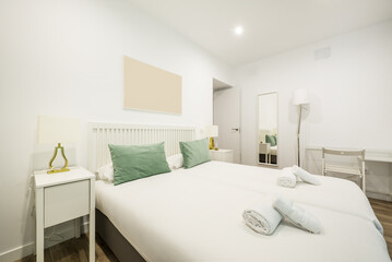 Bedroom with white wooden furniture with a matching desk and towels on the bed