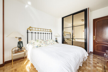 Bedroom with wooden furniture, glossy checkerboard oak parquet flooring and built-in wardrobe with mirror doors