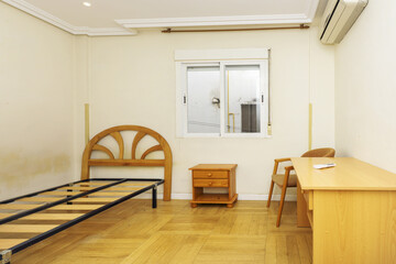 Bedroom with wooden furniture, oak parquet floors and a bed without a mattress