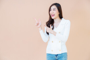 young asia smiling woman with long hair pointing finger. Isolated portrait orange background with copy space