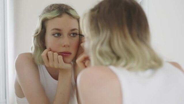 Teenage girl doing makeup with black eyeliner.
