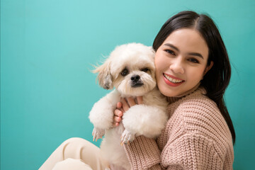 Portrait of Young beautiful woman kisses and hugs her dog over green background.