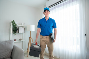 Fototapeta na wymiar An Asian young Technician service man wearing blue uniform checking electrical appliances in home