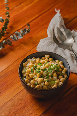 Bowl of cooked chickpeas on warm wooden background