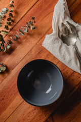 Top view of eptmy dark bowl on wooden background