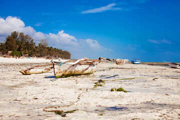 Old fisher boats on the beach during low tide on ocean.