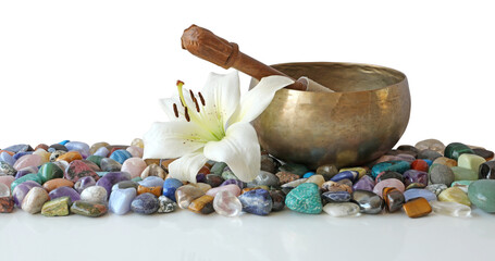 Tibetan singing bowl and mallet on top of many different healing crystals with a lily flower head resting next to bowl transparent png file