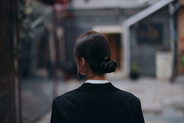 Fototapeta na wymiar Stylish woman in a black jacket walks along the city street with her back to the camera, follow me
