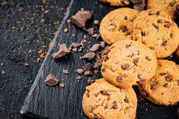 Cookies with pieces of milk chocolate on a stone board. 
