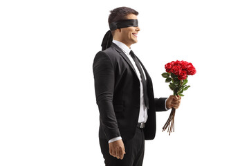 Profile shot of a man in a suit with blindfold holding a bunch of red roses