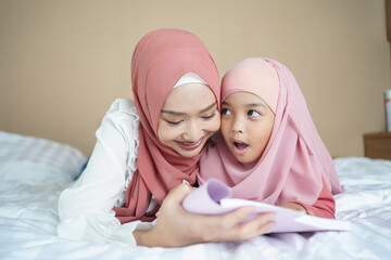 Muslim mother teaching her daughter to read the book.