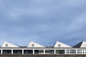 Outdoor exterior view at the detail of saltbox of mix-use industrial building against blue sky. 