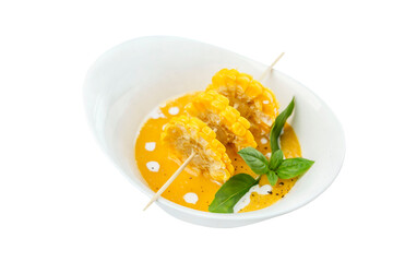 Soup puree from corn in a white plate. Appetizing traditional dish. Close-up. Isolated on white background.
